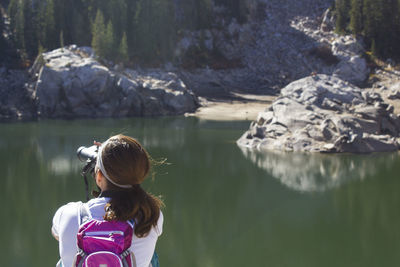 Rear view of woman looking through binocular by lake