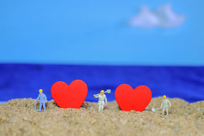 Close-up of heart shape on beach against blue sky