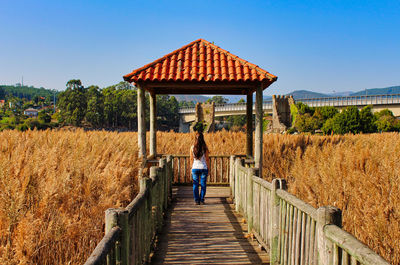 Rear view of woman walking on footpath against sky