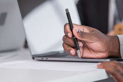 Cropped hand of woman writing in book