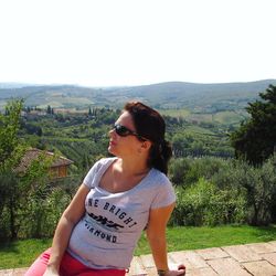 Young woman wearing sunglasses on landscape against clear sky