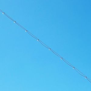 Low angle view of barbed wire against clear blue sky