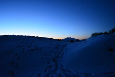 Scenic view of snow covered mountains against clear blue sky