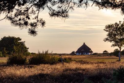 House on field against sky during sunset