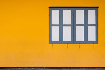 Yellow window on building against orange sky