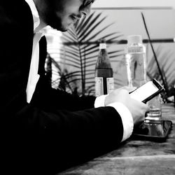 Side view of man holding drink sitting on table