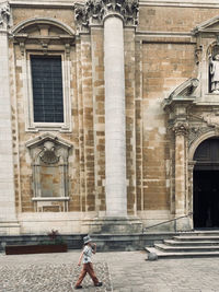 Rear view of woman standing in front of historic building