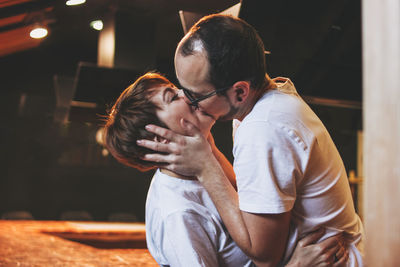 Rear view of couple kissing at home