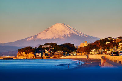 Scenic view of sea and snowcapped mountain against sky during sunrise