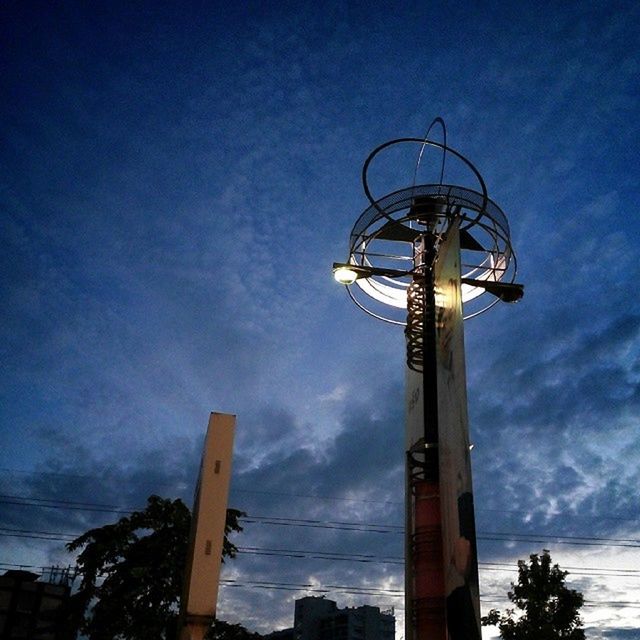 low angle view, sky, blue, built structure, cloud - sky, architecture, tree, tall - high, cloud, outdoors, no people, nature, tower, day, tranquility, technology, dusk, lighting equipment, fuel and power generation, metal