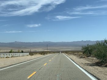 Empty road along landscape against sky