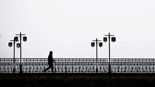 Silhouette man standing on bridge against clear sky