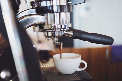 Close-up of machinery pouring coffee in cup