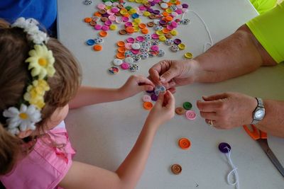 High angle view of girl playing with buttons on table