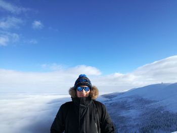Portrait of man standing on snow covered mountain against sky