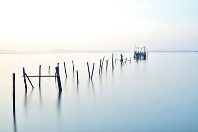 Wooden posts in sea against sky