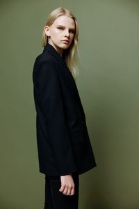 Portrait of young woman standing against gray background