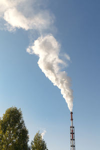 Low angle view of smoke emitting from chimney against sky