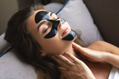 Beautiful woman is relaxing at home with black peel-off mask on her face