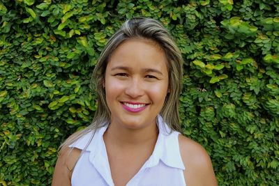 Portrait of smiling young woman against plants