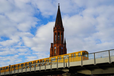 Low angle view of train on railway bridge with church in background