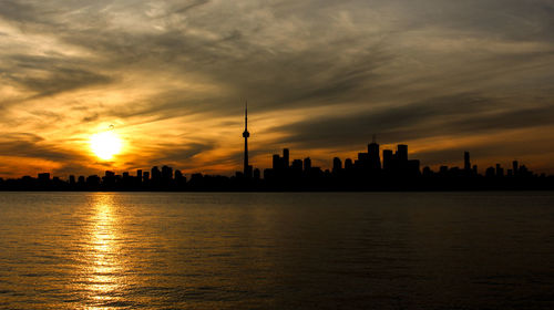 River by silhouette cn tower and city against sky during sunset