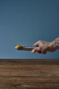 Person holding ice cream on table against blue background