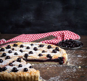 Close-up of tart with black currants on table against black background