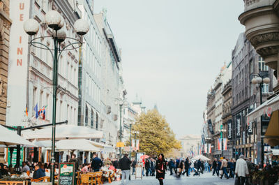People walking on street amidst buildings in city