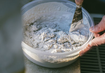 Cropped hand of worker mixing cement in bowl