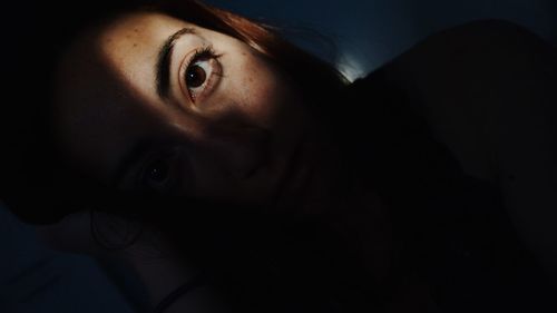 Close-up portrait of young woman in darkroom