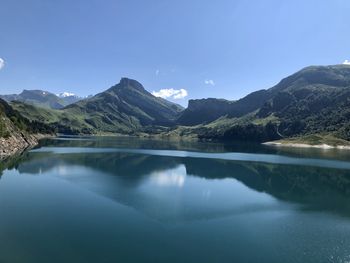 Scenic view of lake and mountains against blue sky