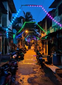 Illuminated street amidst buildings in city at night