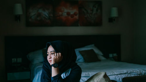 Portrait of woman sitting on bed at home