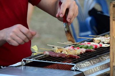 Close-up of man preparing food on barbecue grill