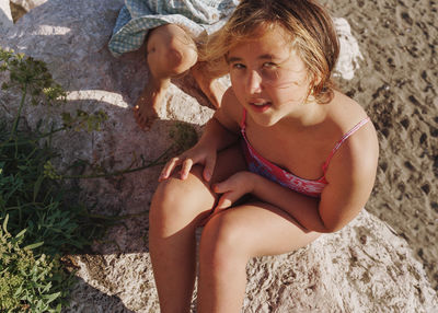 Young girl sitting on rock and looking at camera 