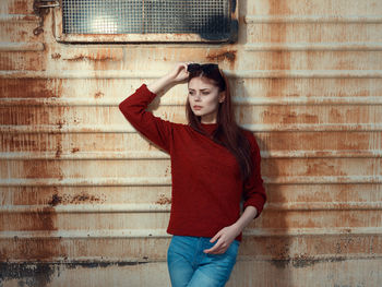 Young woman standing against brick wall