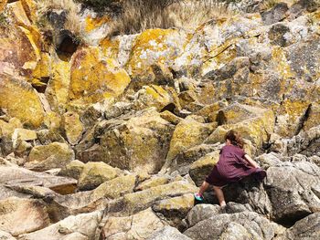 Rear view of woman on rock by mountain