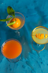 Trio three citrus cocktails orange grapefruit lemon on teal blue background splash mess wet