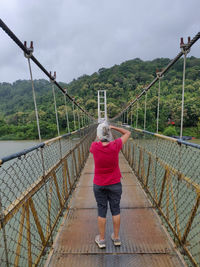 Rear view of woman walking on footbridge