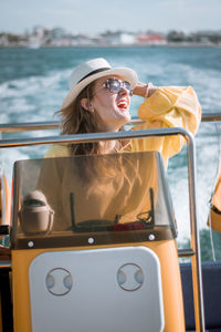 Smiling young woman sitting in boat on sea