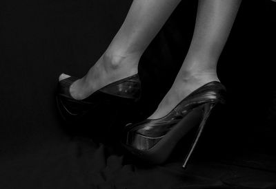 Low section of woman wearing high heels against black background