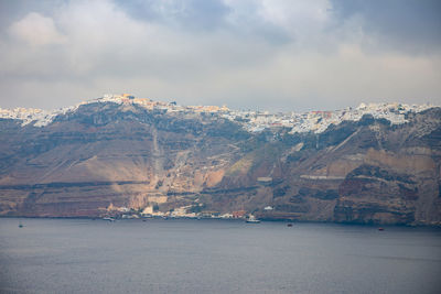 Scenic view of sea by mountains against sky