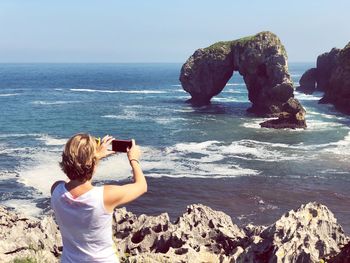 Rear view of photographer photographing sea