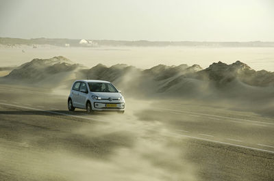 Car on road in desert against sky