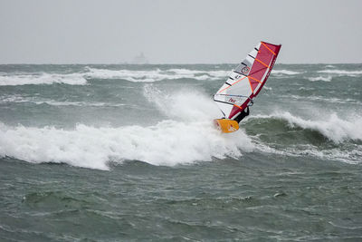 Person paragliding on sea shore