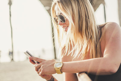 Fashionable woman using phone while sitting in city