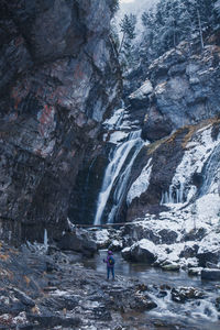 Man standing on rock by waterfall