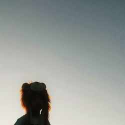 Low angle view of boy wearing lion headwear against clear sky