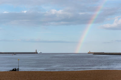 Scenic view of sea against rainbow in sky